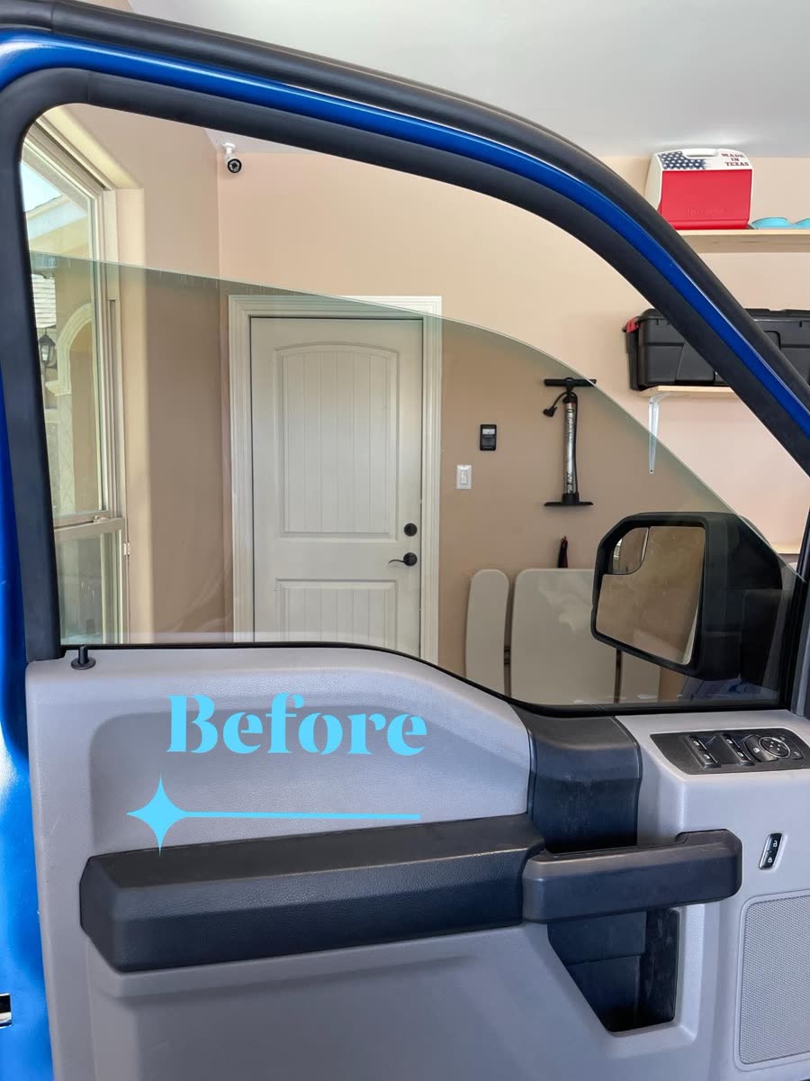 Driver's door window of a blue Ford F-150 before tinting — the garage behind it is fully bright through clear glass